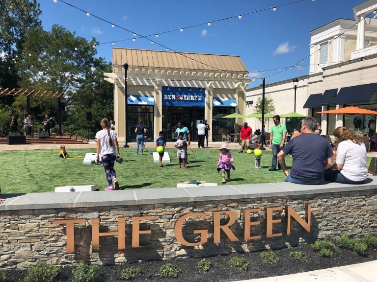 the green at evergreen walk with children playing on the grass in front of Ben and Jerry's